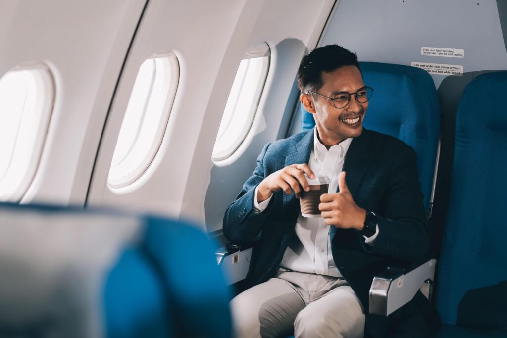 Satisfied businessman passenger drinking hot coffee while sitting on comfortable seat during business travel flight Stock Free