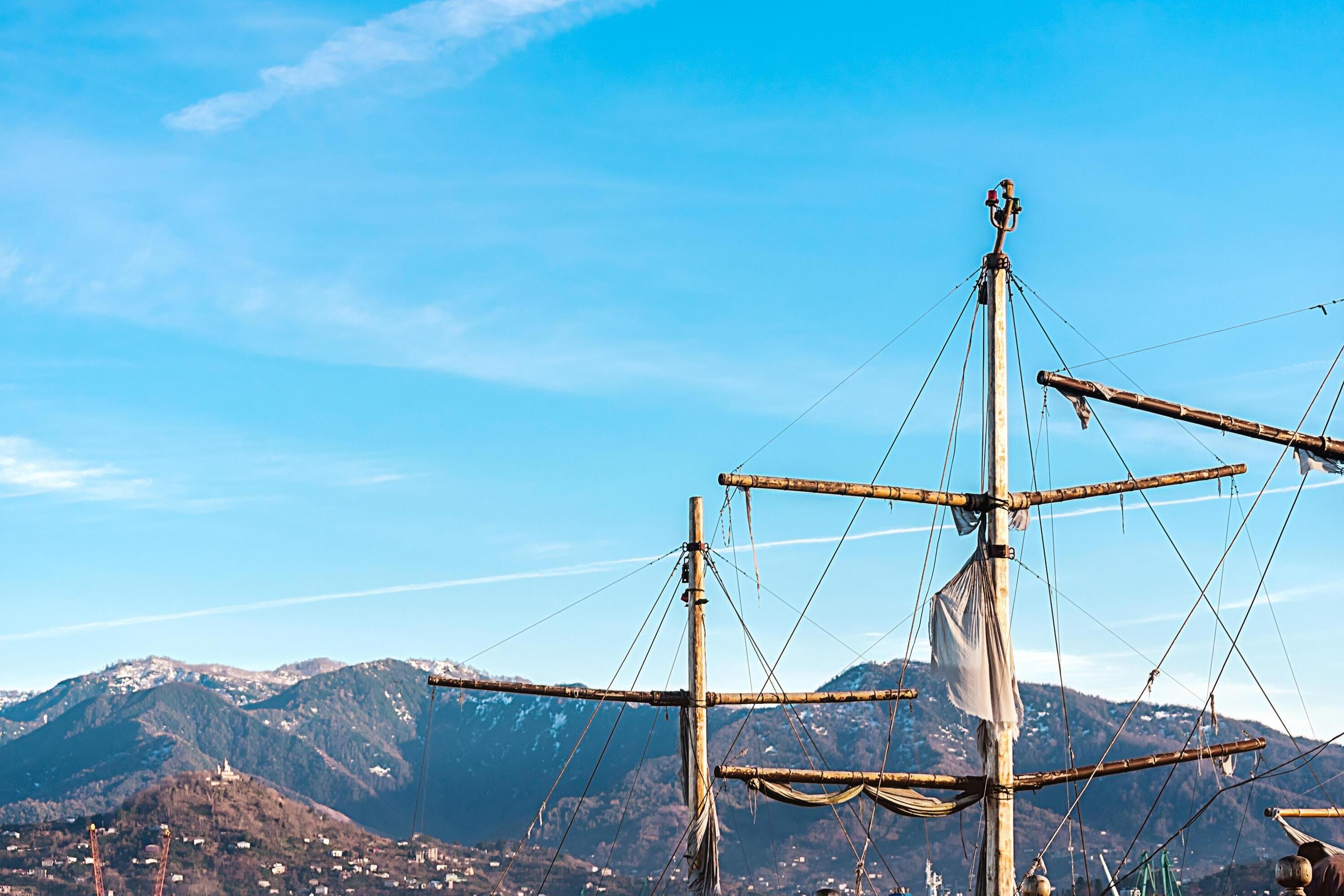 Ship masts against the background of blue sky and mountains. Masts against the backdrop of the Caucasus Mountains. Stock Free