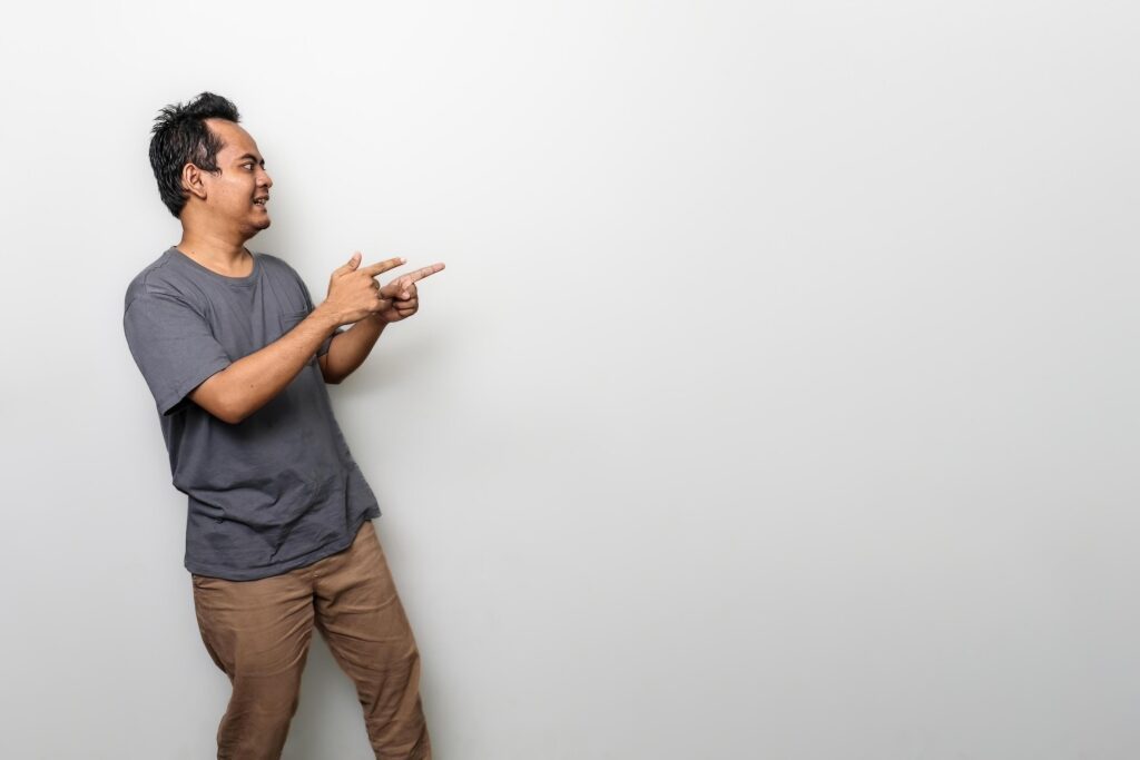 an asian man in gray is pointing something aside with copy space isolated on white background Stock Free