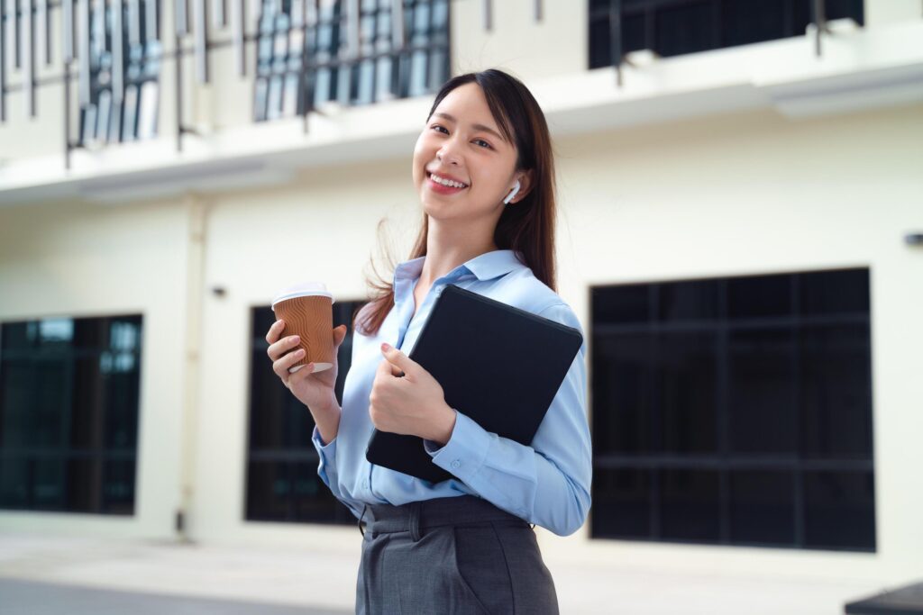 A business woman wearing a blue shirt and holding a cup of coffee and a tablet Stock Free