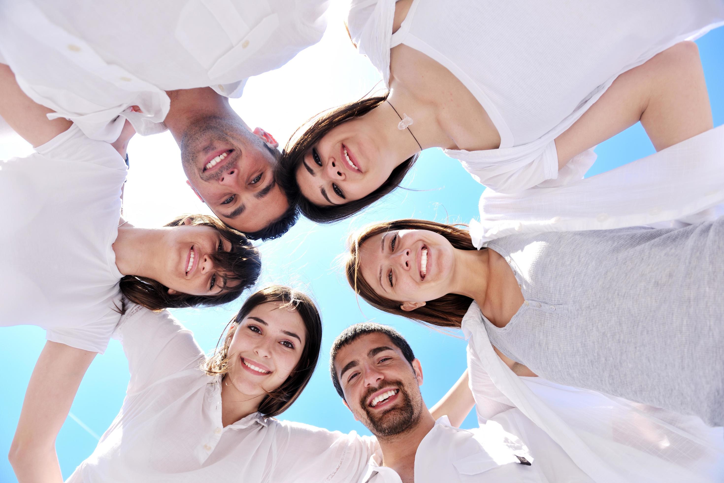 Group of happy young people in circle at beach Stock Free