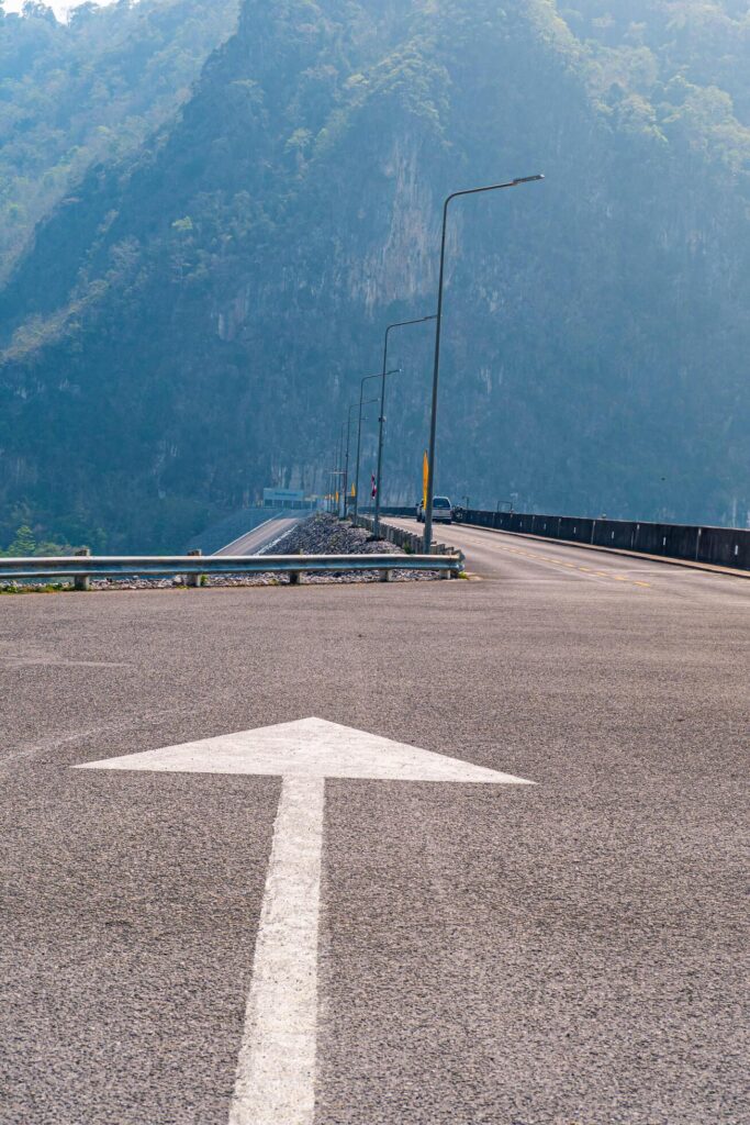 The scene of the road at the top of the dam, with the mountains in the background and a light pole. Stock Free