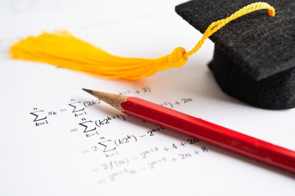 Graduation gap hat and pencil on mathematic formula exercise test paper in education school. Stock Free