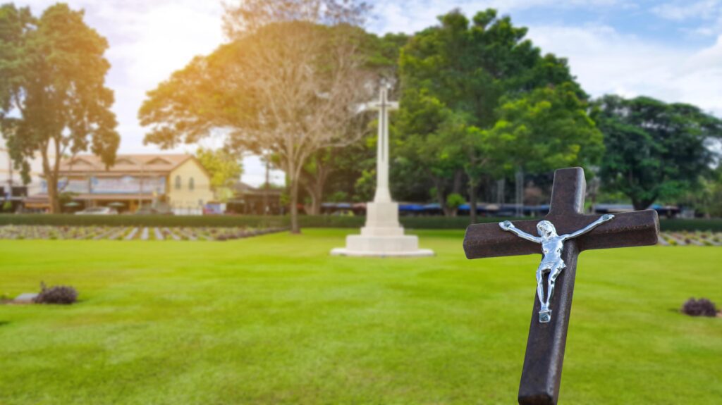 A red wooden cross on a blurred cemetery background. Stock Free