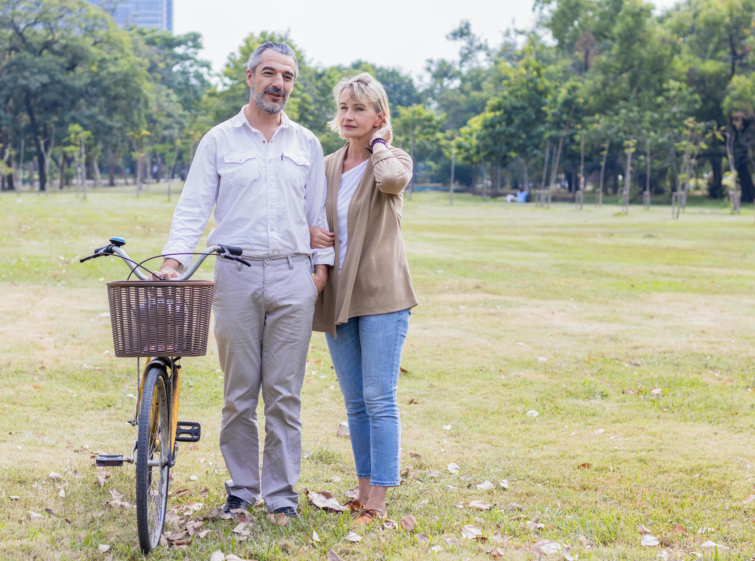 Caucasian elders happily stroll in the park with a bicycle Stock Free