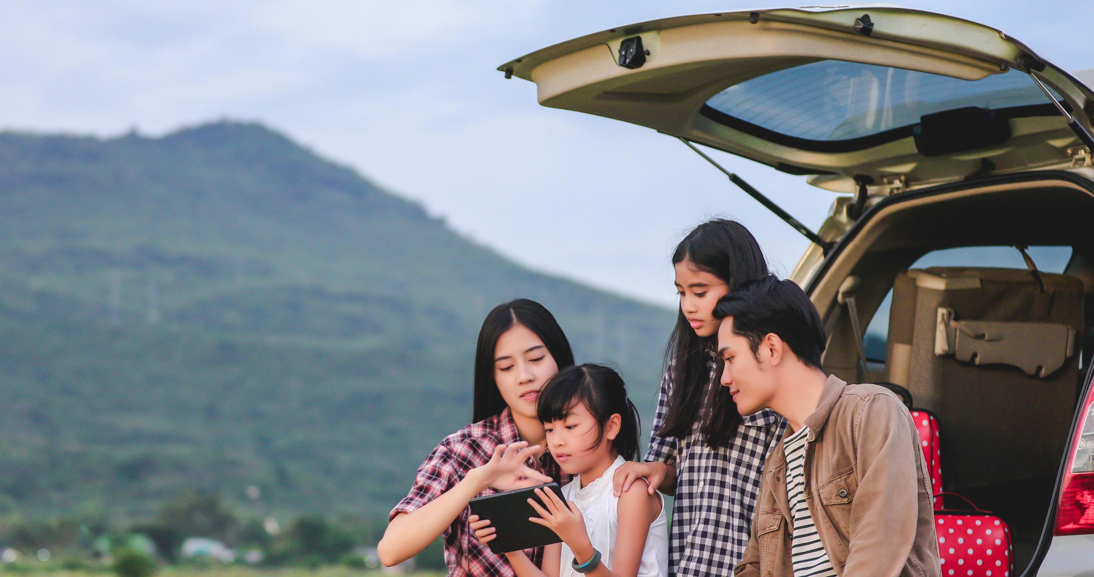 Happy little girl with asian family sitting in the car for enjoying road trip and summer vacation in camper van Stock Free