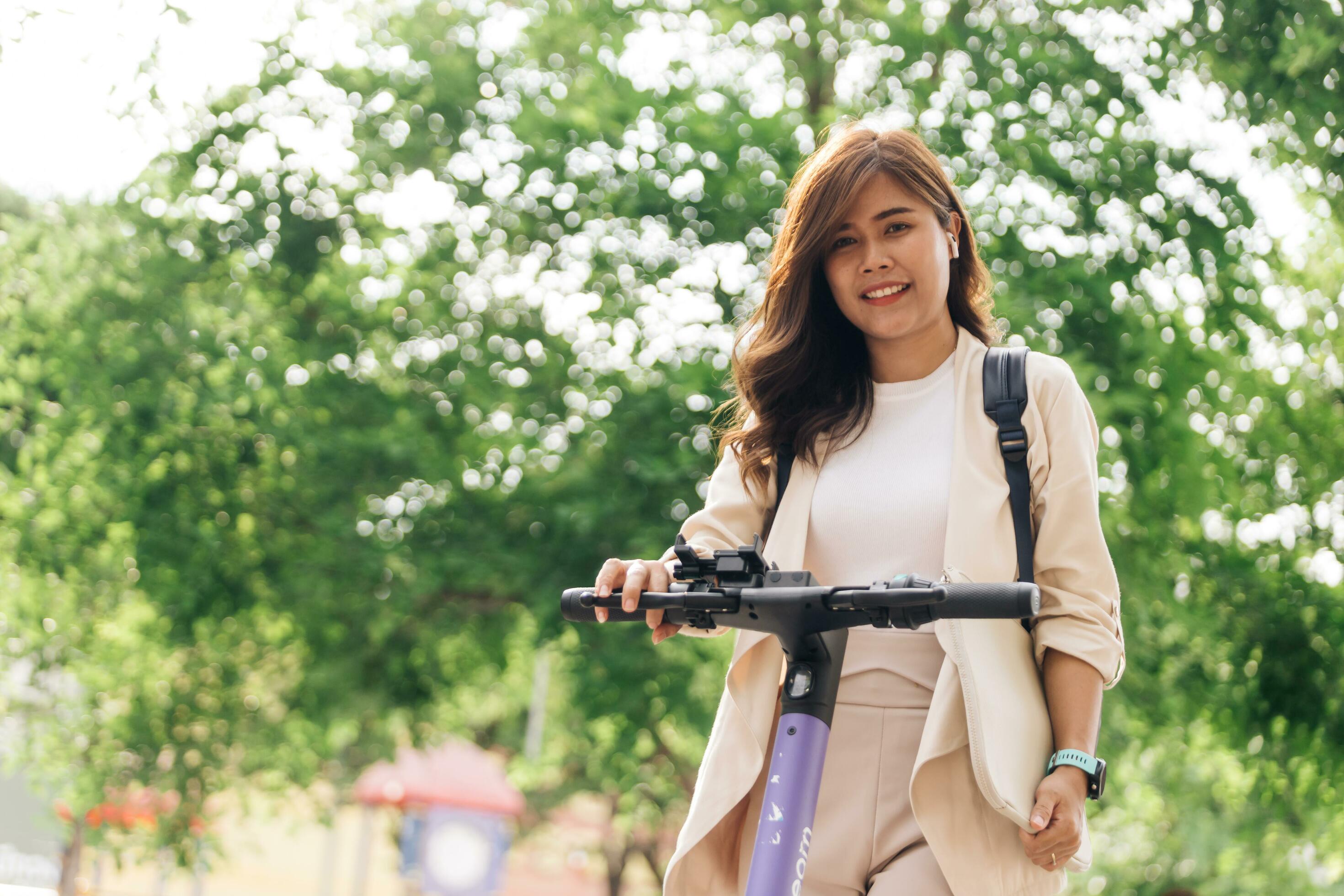 asian woman riding electric scooter in the park, lifestyle concept Stock Free