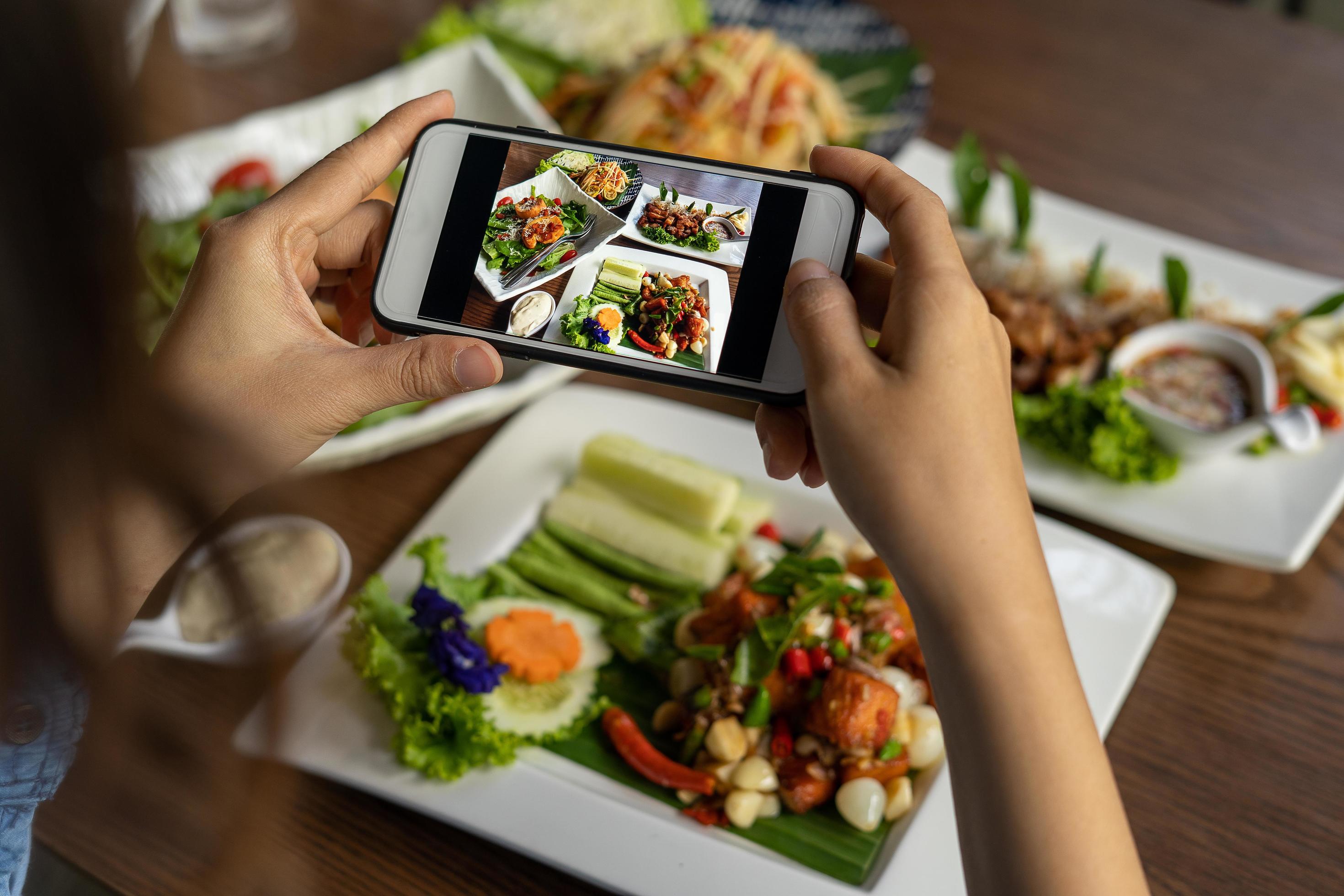 Woman take picture of a meal on the table after ordering food online to eat at home. Photography and use phone concepts Stock Free