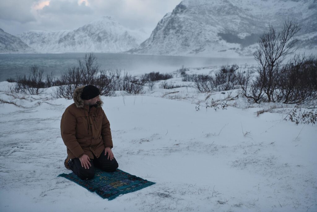 Muslim traveler praying in cold snowy winter day Stock Free