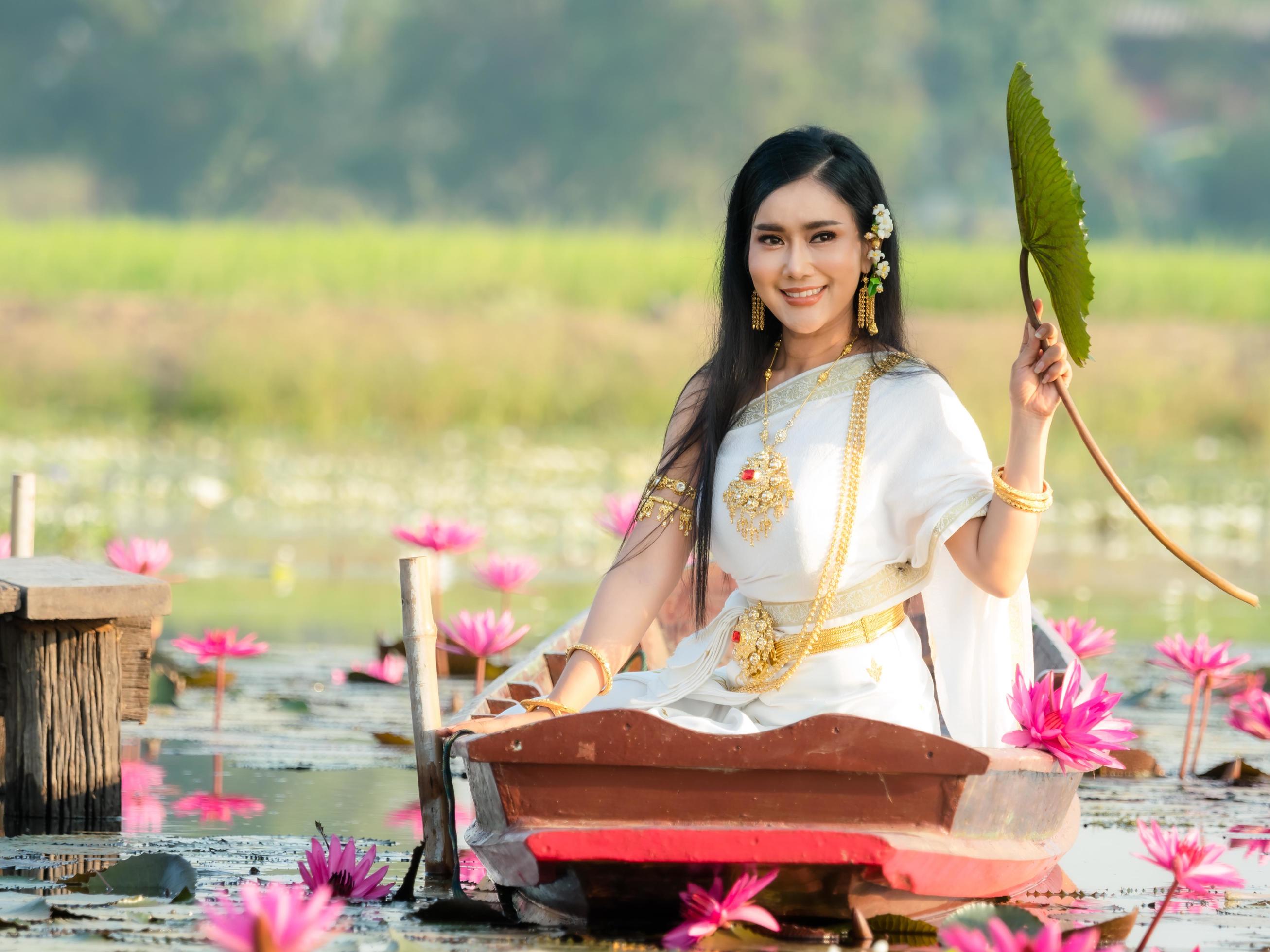 An elegant Thai woman wearing traditional Thai clothes carrying lotus flowers leaf collected from a lotus field Stock Free