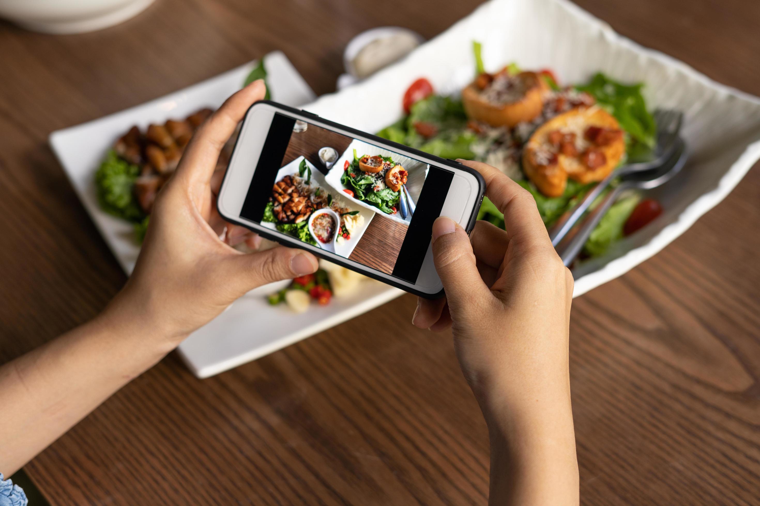 Woman take picture of a meal on the table after ordering food online to eat at home. Photography and use phone concepts Stock Free