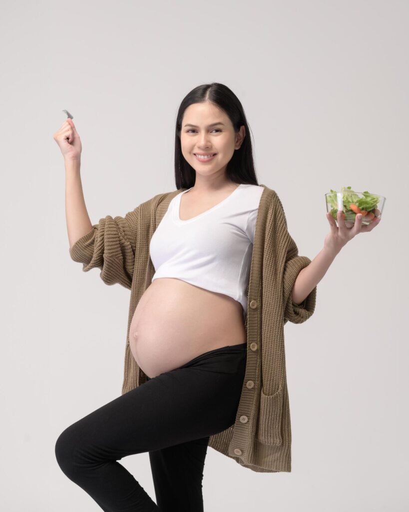 Portrait of Beautiful pregnant woman eating salad over white background studio, health and maternity concept Stock Free