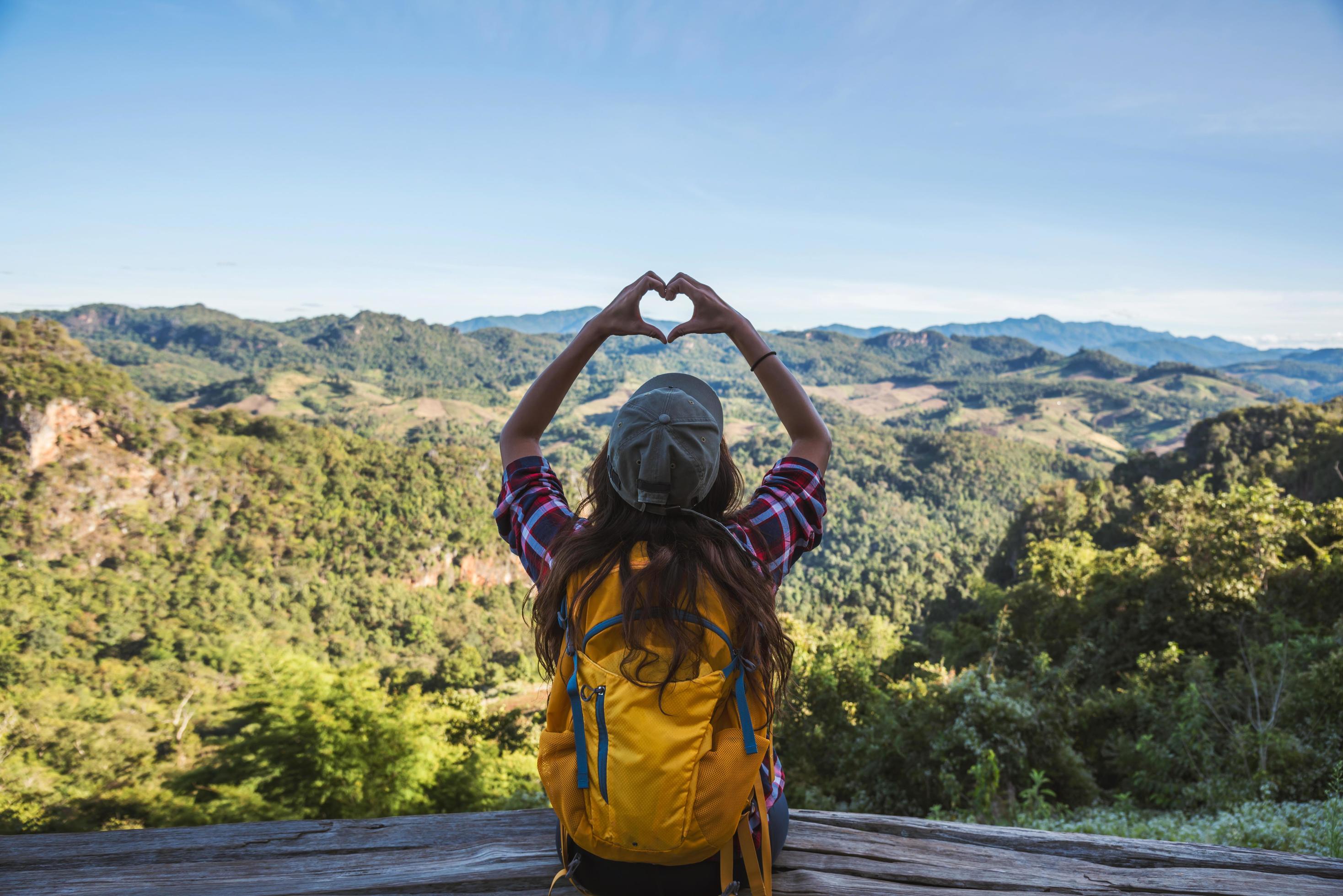 Young woman Tourists with backpacks Happy to travel She raised her hand to make a heart shape and enjoy the natural scenery on the mountain. Stock Free