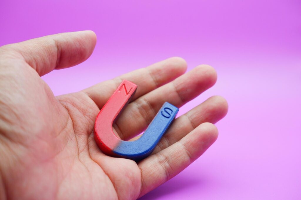 hand holding a horseshoe magnet isolated on a purple background Stock Free