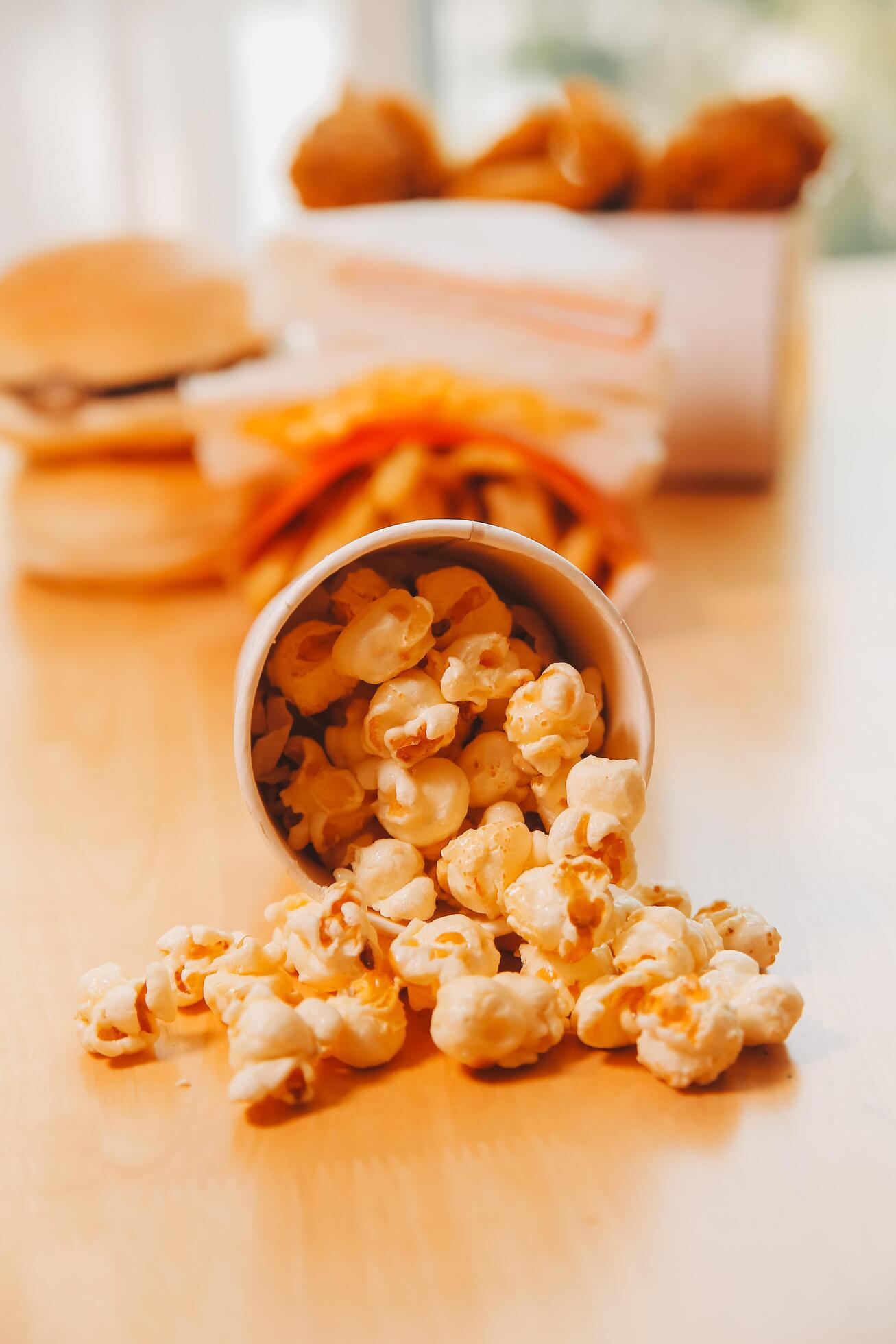 A bucket of popcorn, top-view, warm colors, light brown wooden background, flat lay, daylight macro close-up Stock Free