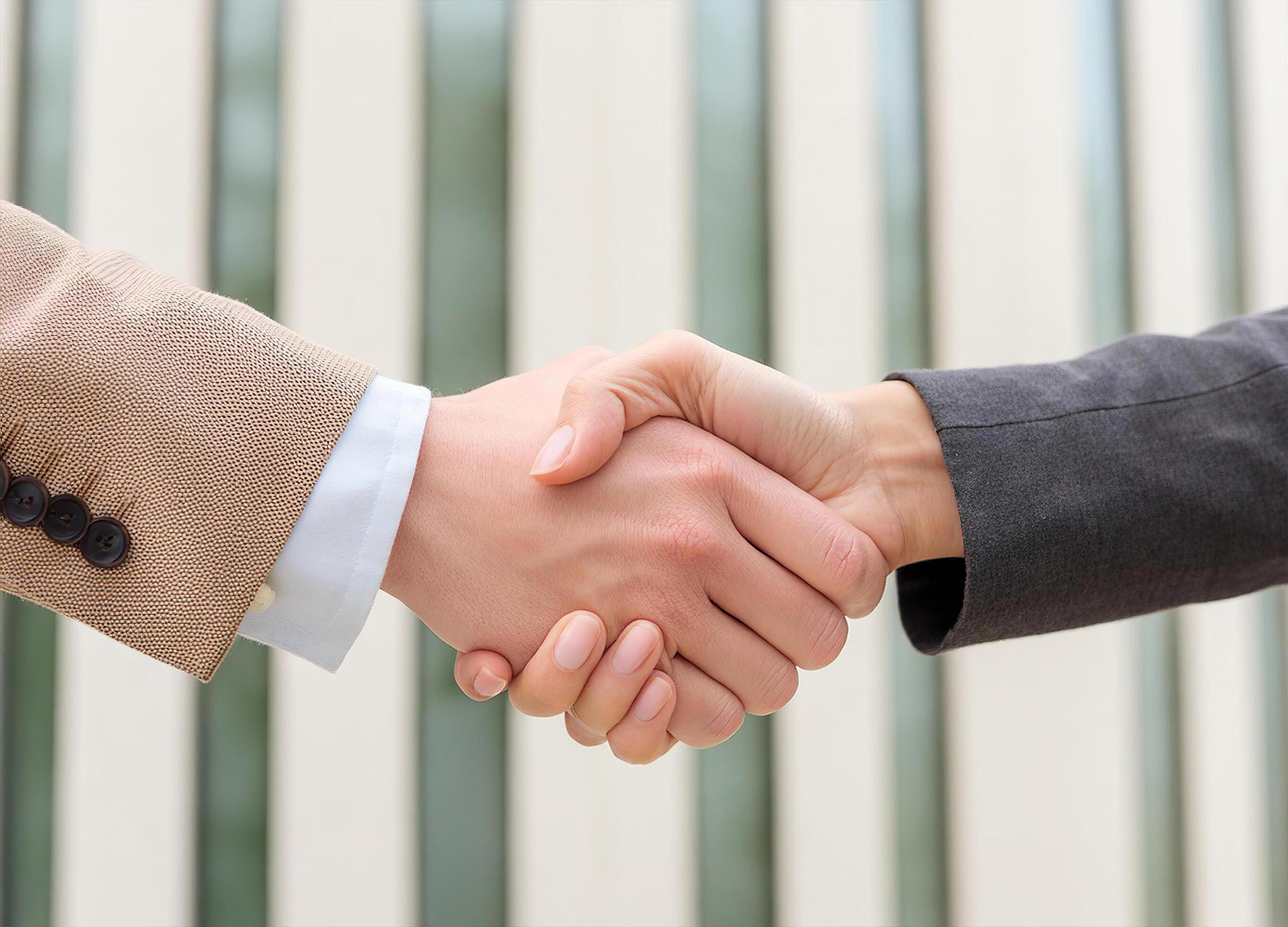 Close up of hand of Two business people shaking hands,blurred building background Stock Free