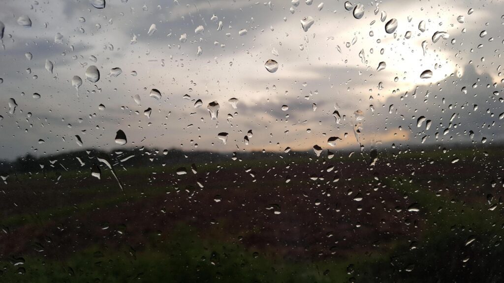 Rainwater drops cover on glass with cloud background Stock Free