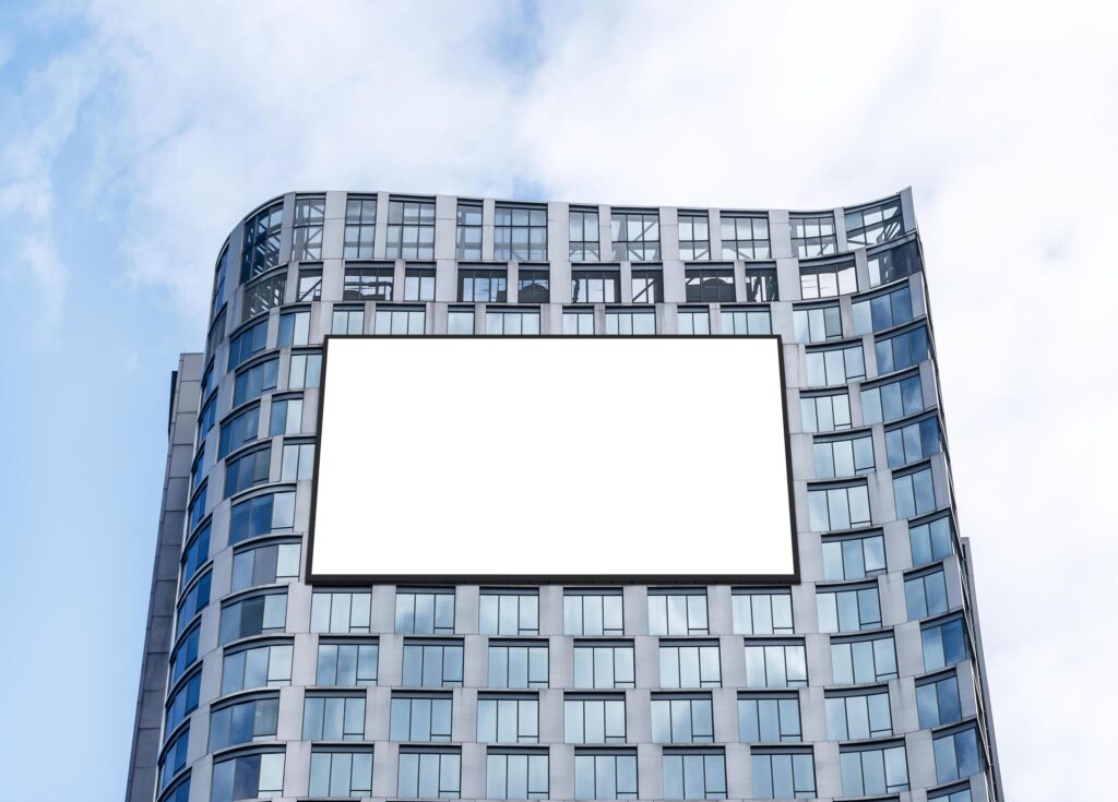 Mock up white horizontal large LED display billboard on tower building with blue sky background .clipping path for mockup Stock Free