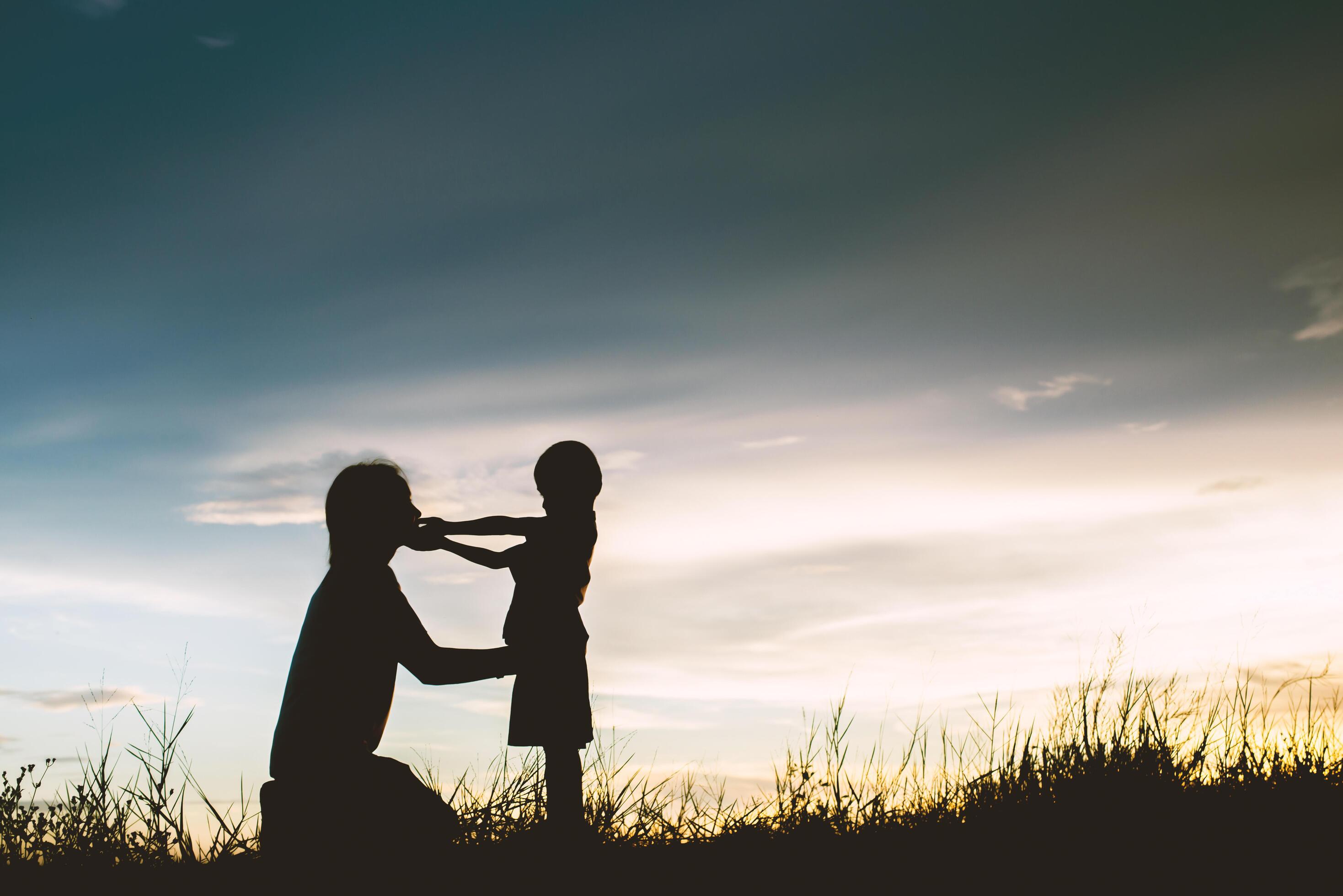 Mother encouraged her son outdoors at sunset, silhouette concept Stock Free