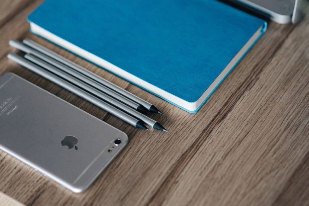 Silver iPhone with a blue notebook and pencils Stock Free