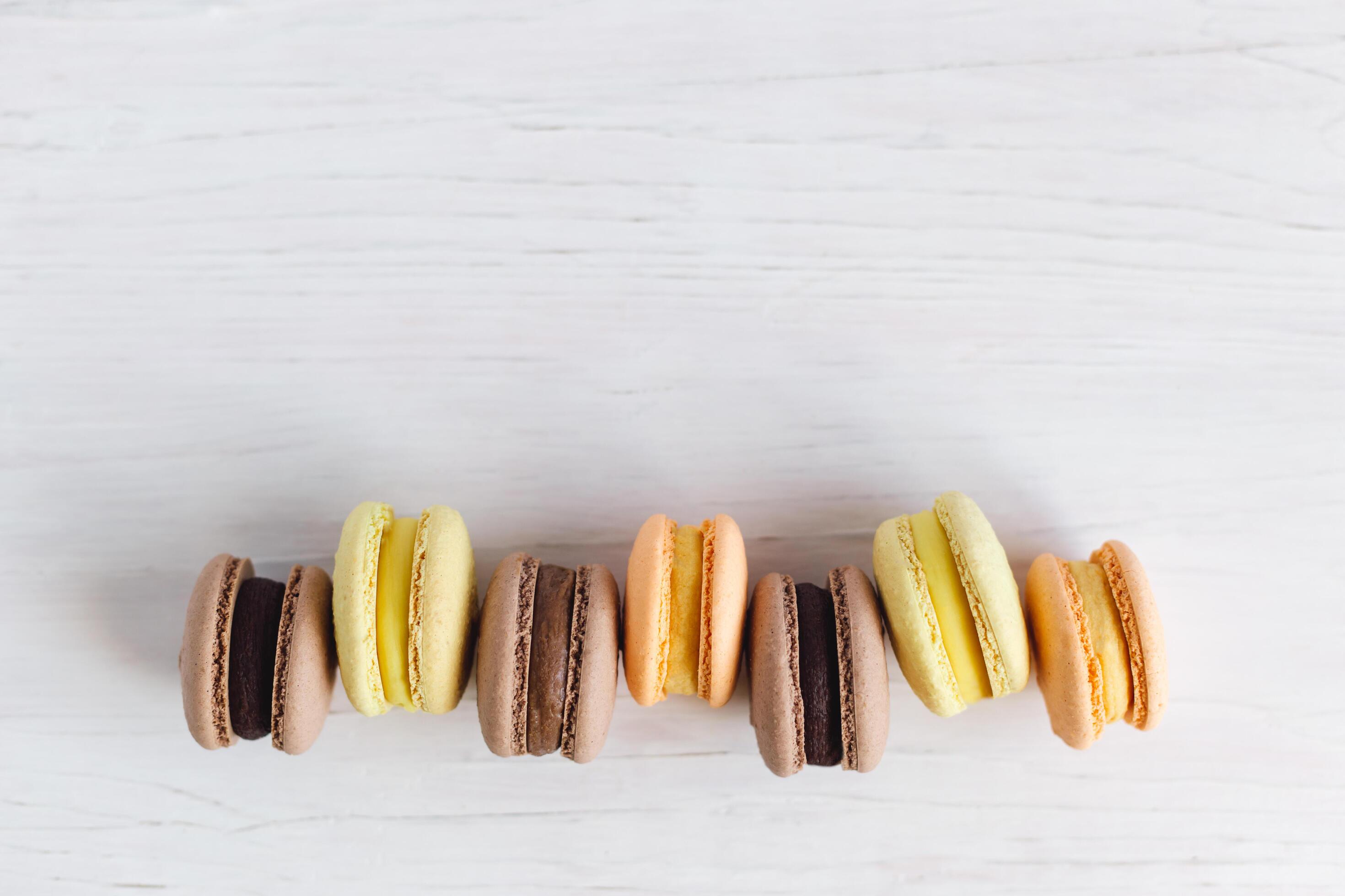 Tasty french macarons on a white wooden table. White background, pastel colors. Stock Free