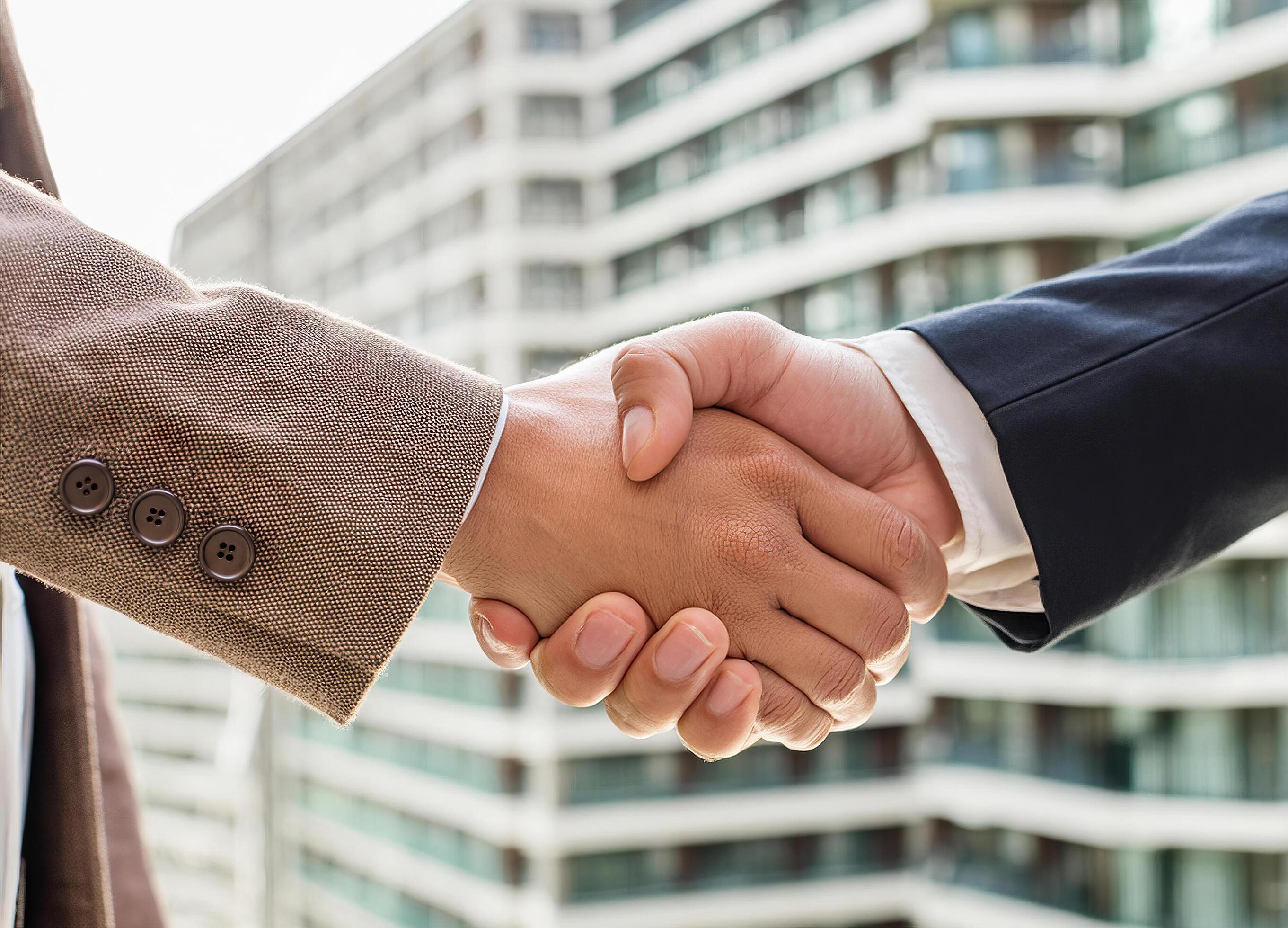 Close up of hand of Two business people shaking hands,blurred building background Stock Free