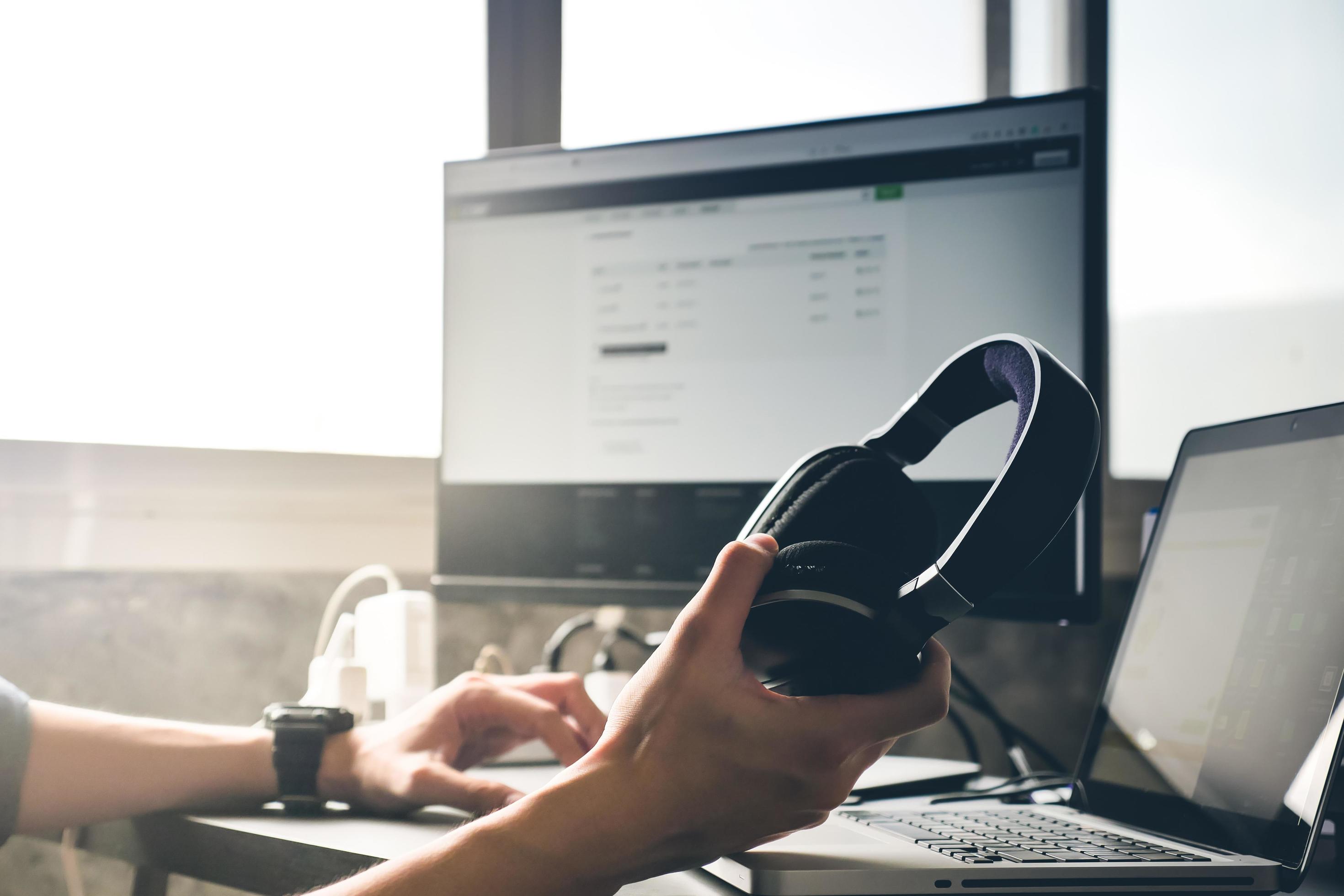 Male hands holding headphones and working on computer Stock Free