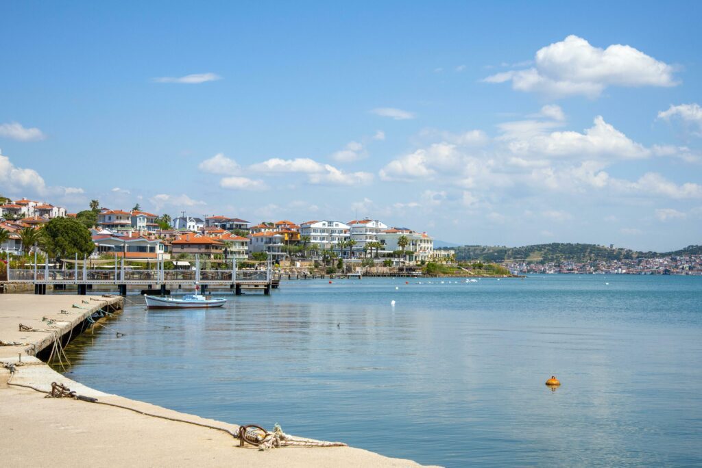 A promenade in Turkey, Ayvalik city. A boat and houses on the city’s waterfront on a sunny summer day. Stock Free