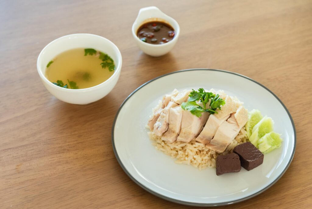 Traditional Singapore chicken rice with salted soybeans sauce and soup on wooden background Stock Free