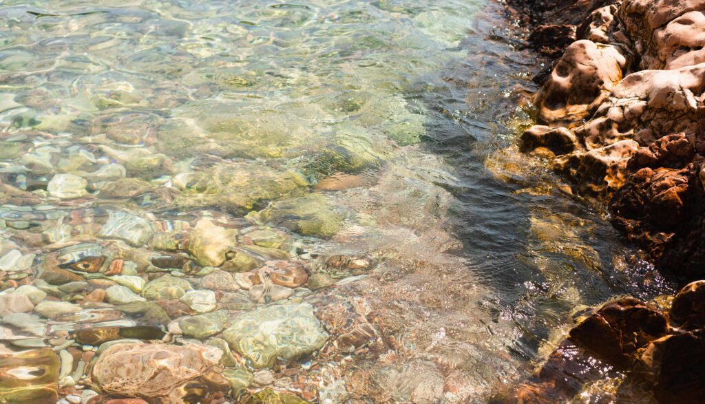 Sea stones in the sea at summer sunny day. Nautical background of pebbles. Seascape. Selective focus. Stock Free