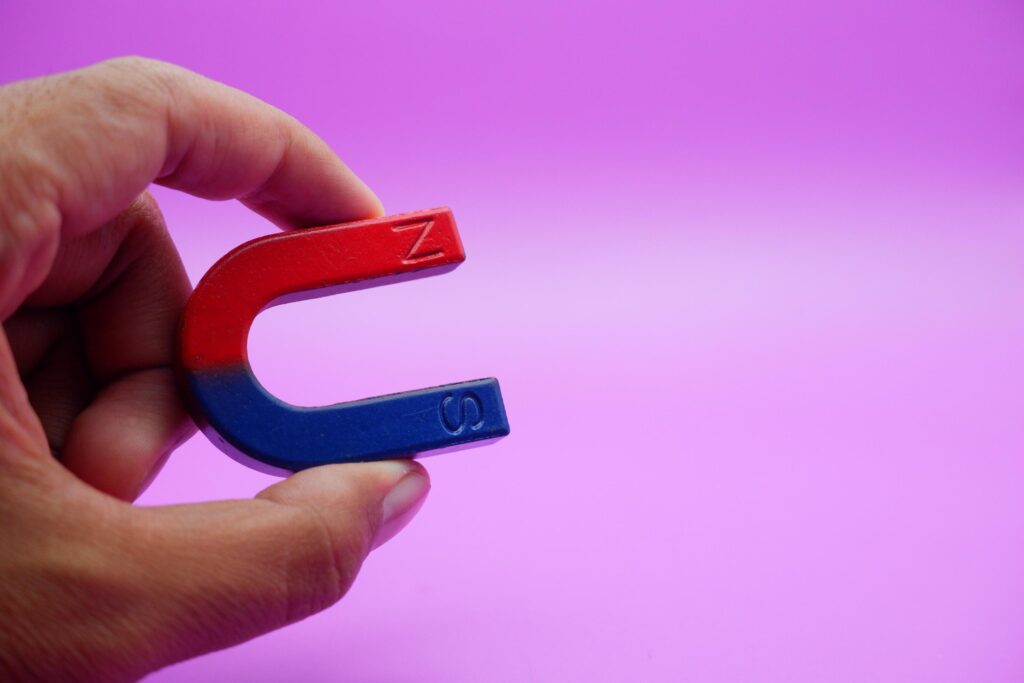 hand holding a horseshoe magnet isolated on a purple background Stock Free