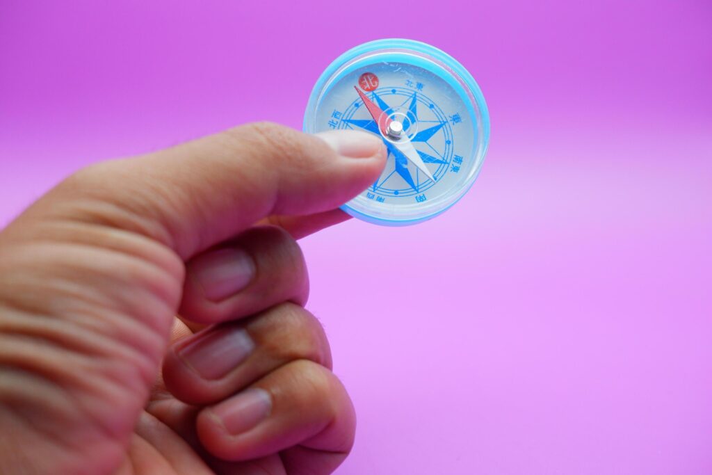 hand holding a compass isolated on a purple background Stock Free