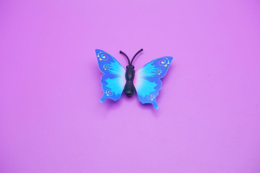 butterfly toy isolated on purple background. toy butterfly with blue wings. Stock Free