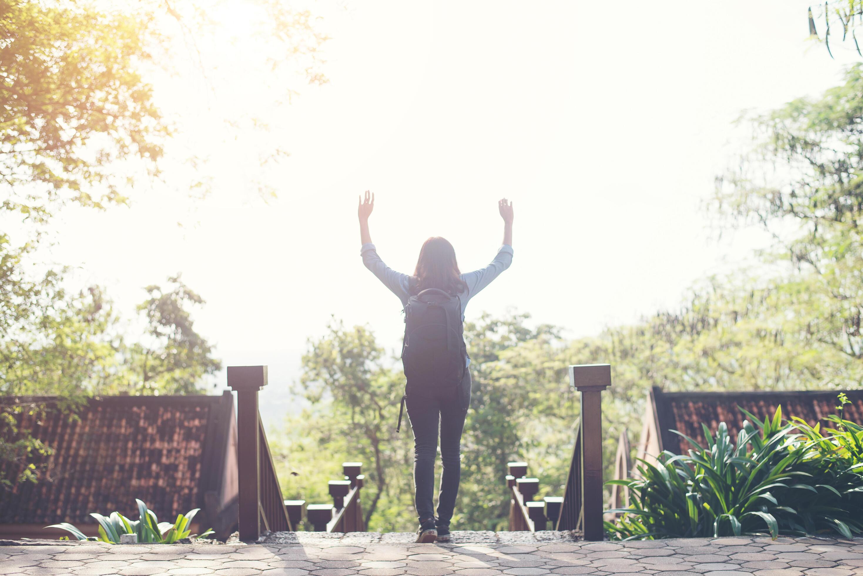 Freedom traveler hipster woman standing with raised arms and enjoying a beautiful nature. Achieved with adventure. Stock Free