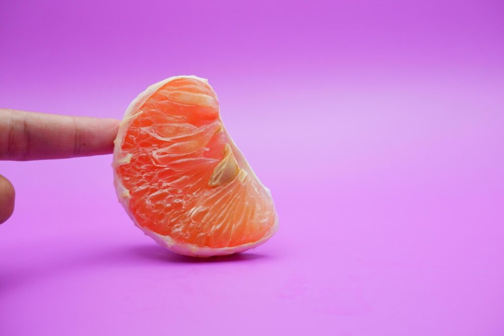 a slice of grapefruit isolated on a purple background. grapefruit that has been peeled until the grain of the orange is visible Stock Free