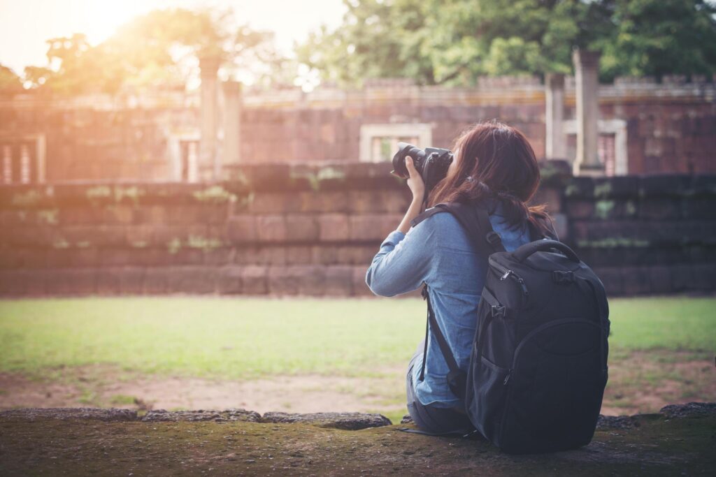 Young attractive woman photographer tourist with backpack coming to shoot photo at ancient phanom rung temple in thailand. Stock Free