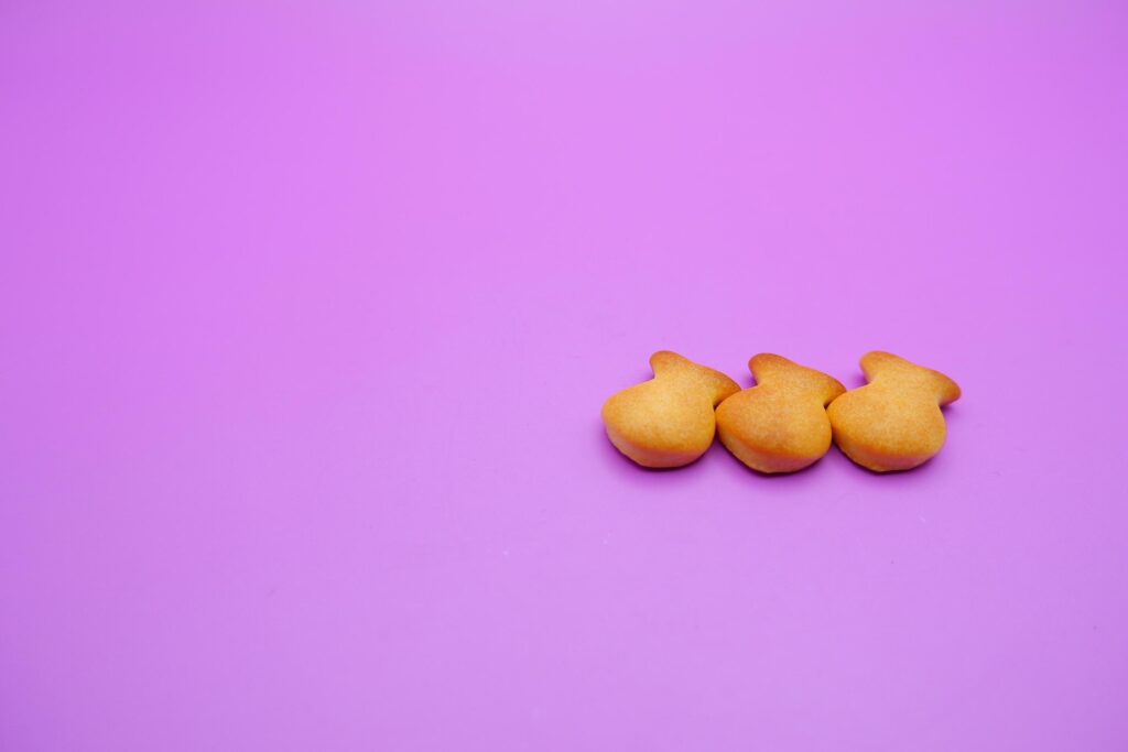 three biscuits shaped like fish isolated on a purple background Stock Free