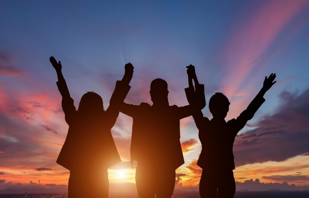 Three people silhouetted in front of sunset Stock Free