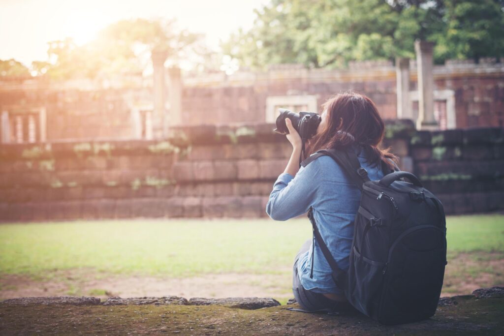 Young attractive woman photographer tourist with backpack coming to shoot photo at ancient phanom rung temple in thailand. Stock Free