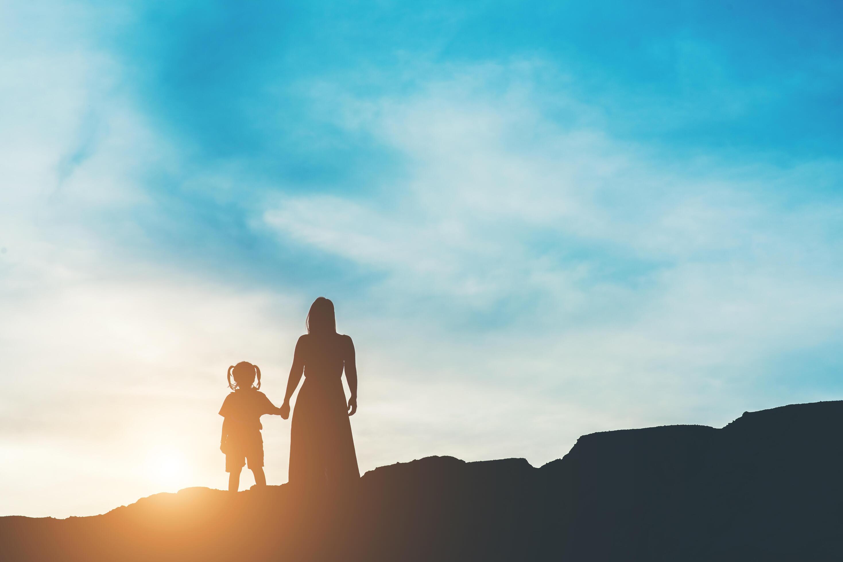 Silhouette of mother with her daughter standing and sunset Stock Free