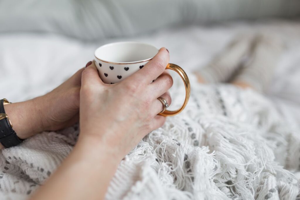 Soft photo of woman on the bed with the book and cup of coffee in hands Stock Free