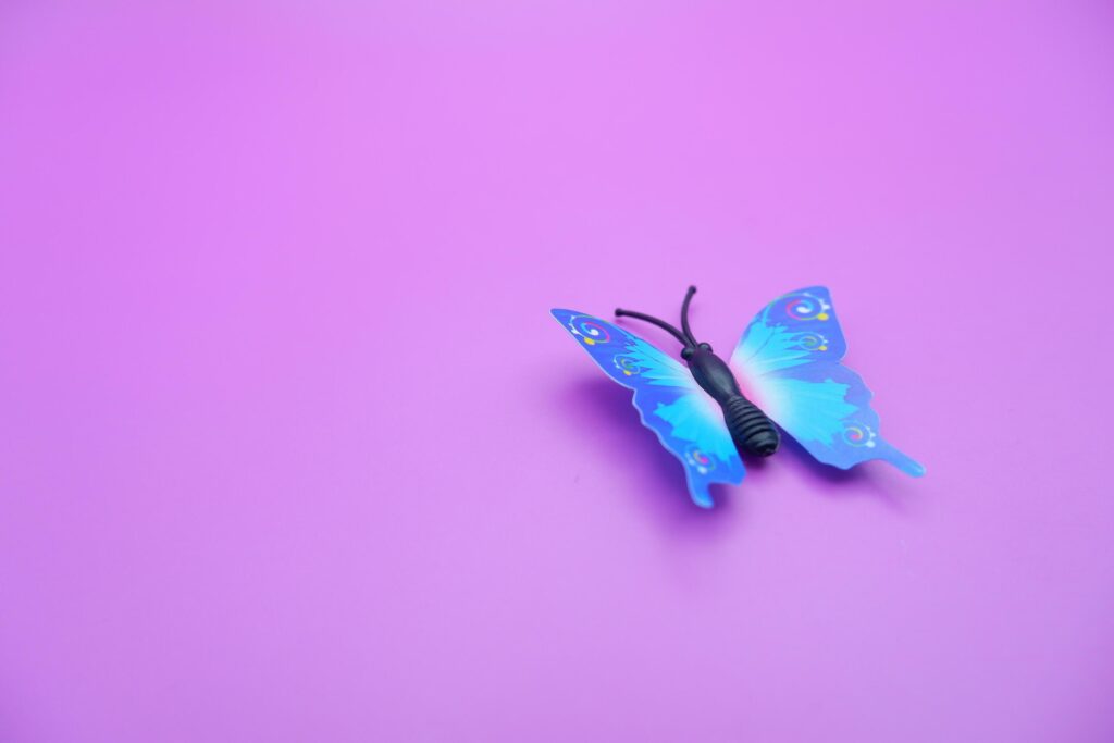 butterfly toy isolated on purple background. toy butterfly with blue wings. Stock Free