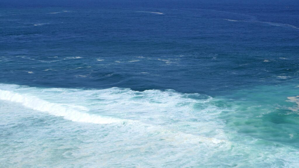 Front view over the ocean and white foam waves. Feel calm, cool, relaxed. Idea for cool background and copy space above. Stock Free