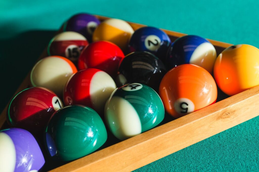 Billiard balls on green table with billiard cue Stock Free