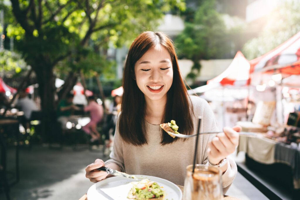 Young adult asian woman eat lunch food at restaurant outdoor on weekend day Stock Free