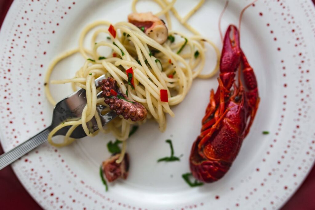 
									Fancy dinner with seafood pasta, crayfish and red wine by the table decorated with roses Stock Free