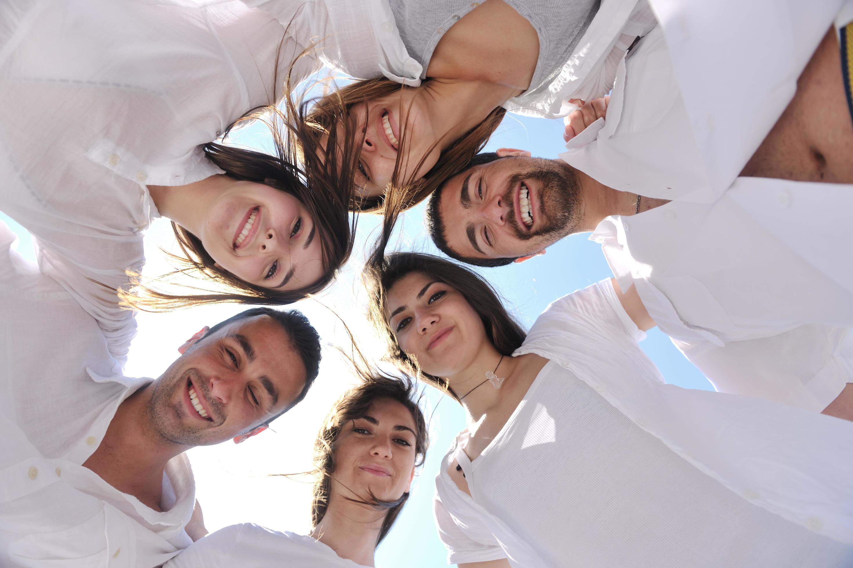 Group of happy young people in circle at beach Stock Free