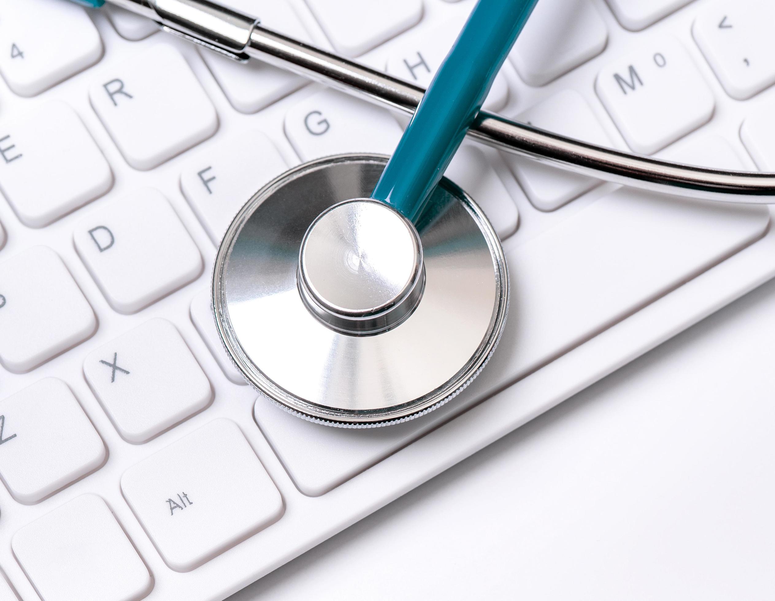 Stethoscope on computer keyboard on white background. Physician write medical case long term care treatment concept, close up, macro, copy space Stock Free