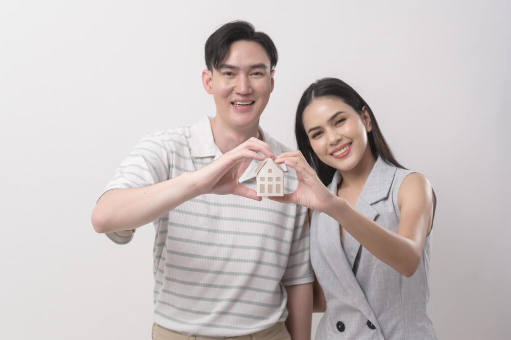 Happy couple of love holding small house over white background Stock Free