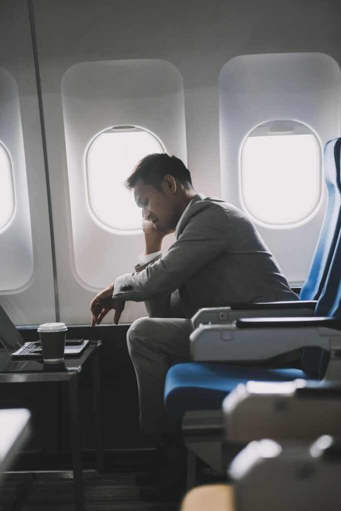 Stressed and professional Asian businessman in a business class, having a serious phone call with someone during the flight to a business meeting. Stock Free